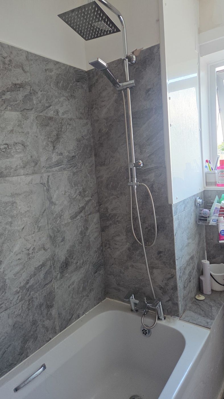 Gri mermer görünümlü fayans ve krom duş setiyle tamamlanmış banyo
